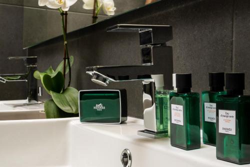 a bathroom sink with green bottles of soap and a faucet at NV Illusion in Chania Town