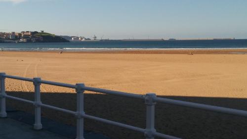 a view of a beach with a fence and the ocean at La Casita de la cruz in Langreo