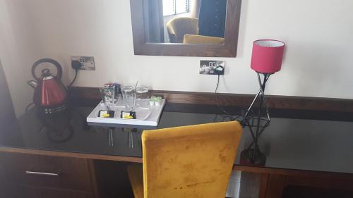 uma secretária com uma cadeira amarela e um candeeiro vermelho em The Castle Hotel Neath em Neath