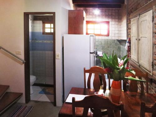 a kitchen with a table and a white refrigerator at Chalés na Hora in Olinda