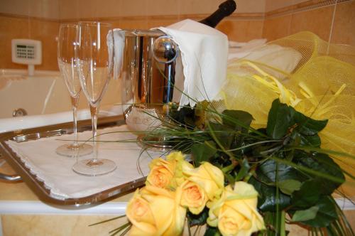 a counter with two wine glasses and a bouquet of roses at Hotel Motel Gold in Calcinate