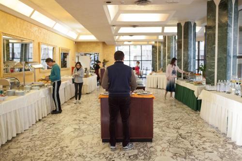 a man standing at a counter in a restaurant at Hotel Diplomat Palace in Rimini