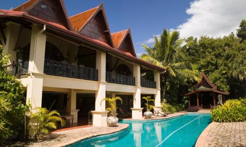 a villa with a swimming pool in front of it at Rico Resort in Chiang Kham