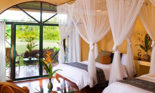 a bedroom with two beds and a large window at Rico Resort in Chiang Kham