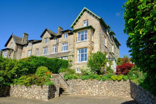 a large stone house with a stone wall at Corner Beech House in Grange Over Sands