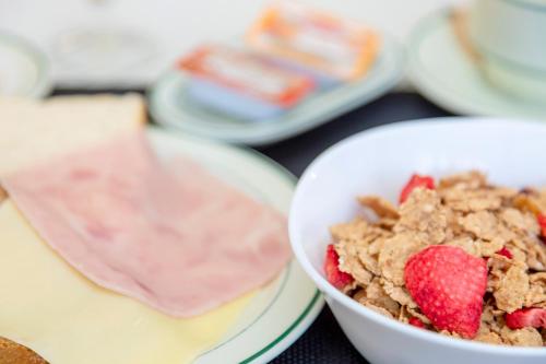 a bowl of cereal and a bowl of strawberries at Hostal Molins Park in Ibiza Town