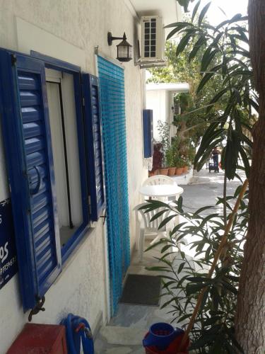 a building with blue shutters and a table in a courtyard at Angelos Rooms in Myrtos