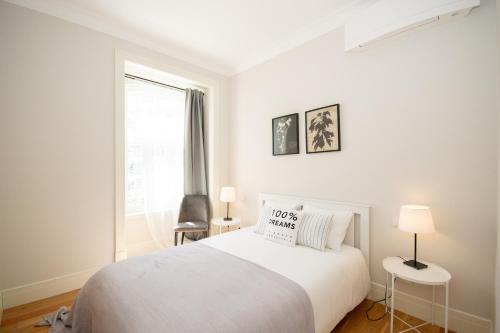 ein weißes Schlafzimmer mit einem weißen Bett und einem Fenster in der Unterkunft Cosy Marques de Pombal Apartment in Lissabon