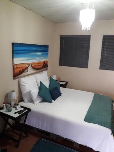 a bedroom with a large white bed with green pillows at Relax in Joy & Mignon for a bushveld Feeling in Bloemfontein