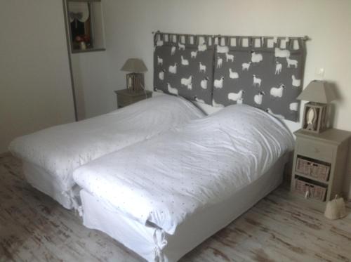 a bedroom with a bed with white sheets and a headboard at O Mylle Douceurs in Le Crotoy