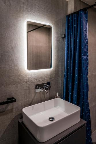 a bathroom with a white sink and a blue shower curtain at Alla Riva in Verona