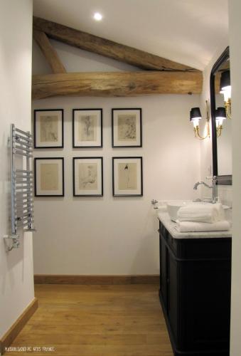 La salle de bains est pourvue d'un lavabo et de dessins encadrés sur le mur. dans l'établissement Maison Saint-Pé (Gers), à Béraut