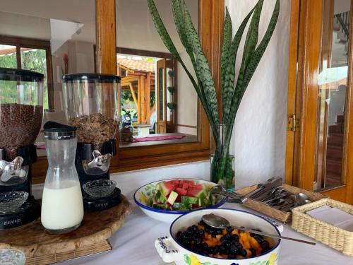 a table with a bowl of fruit and a bowl of milk at Finca Hotel Santana in Montenegro