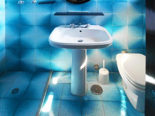 ガリポリにあるAppartamento vico Gelsominiの青いタイル張りのバスルーム(洗面台、トイレ付)
