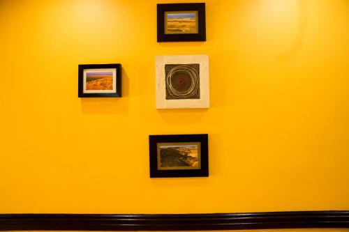 a yellow wall with pictures on it at A-Z Boutique Guesthouse in Windhoek