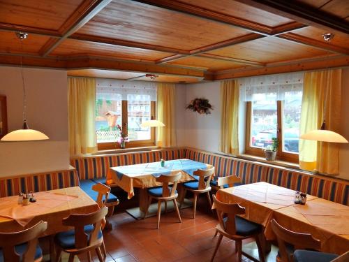 un ristorante con tavoli e sedie in legno e finestre di Ski & Bike Pension Maria a Saalbach Hinterglemm
