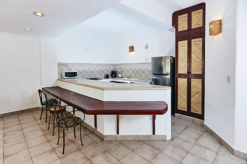 a kitchen with a bar with chairs and a refrigerator at Hotel Suites Ixtapa Plaza in Ixtapa