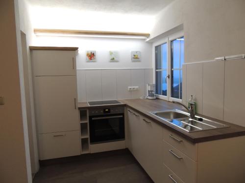 a kitchen with white cabinets and a sink and a window at Ferienwohnungen Schöbringer in Weyregg