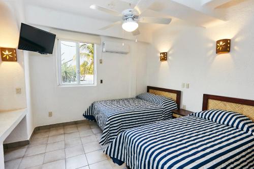 a room with two beds and a ceiling fan at Hotel Suites Ixtapa Plaza in Ixtapa