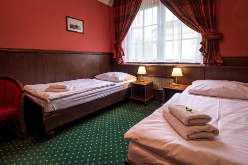 two beds in a room with red walls and a window at Hotel U Hejtmana Šarovce in Uherské Hradiště