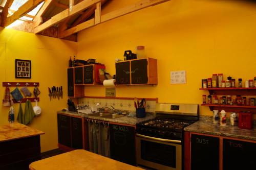 a kitchen with a stove and a yellow wall at Sven's Basecamp Hostel in Fairbanks