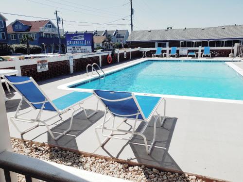 two blue chairs sitting next to a swimming pool at Colonial Inn in Nags Head