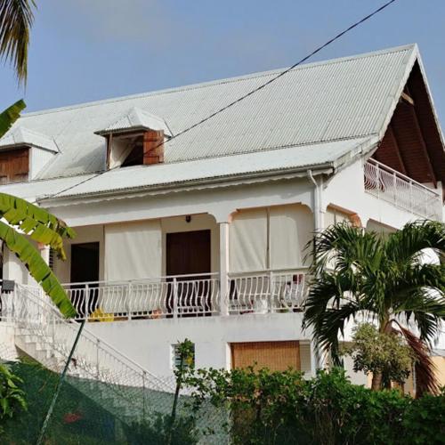 a white house with a balcony and a palm tree at villa siber in Port-Louis