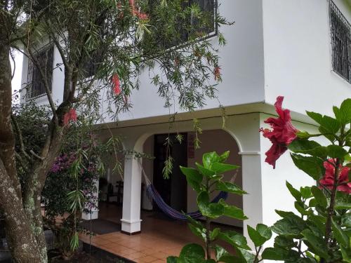 a front porch of a house with red flowers at Casa del Peregrino Santo Thomas in Baños