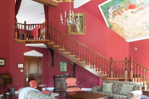 a living room with red walls and a wooden staircase at Wedmore Place in Williamsburg