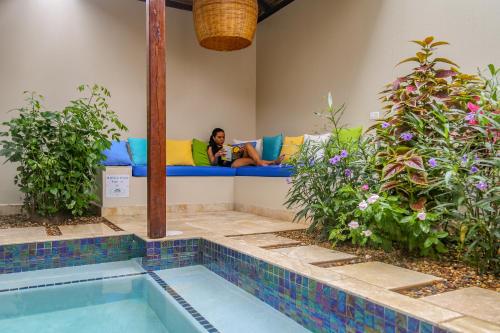 a woman sitting on a couch taking a picture of a pool at Almond Beach Resort at Jaguar Reef in Hopkins