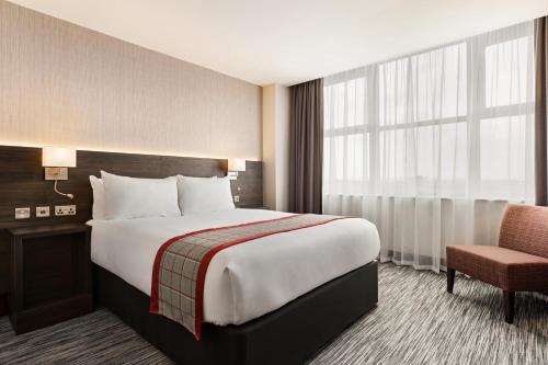 a hotel room with a large bed and a chair at Ramada East Kilbride in East Kilbride