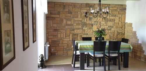 a dining room table with chairs and a stone wall at Zielona Mila Dom Wakacyjny in Cekcyn