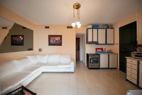 a living room with a white couch and a kitchen at Afroditi in Glyfada