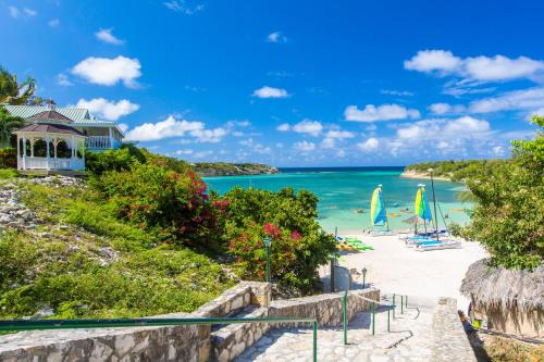 a beach with chairs and umbrellas and the ocean at The Verandah Antigua - All Inclusive - Adults Only in Willikies