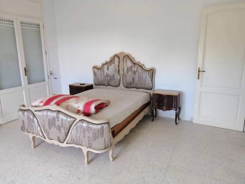 een slaapkamer met een groot bed met een houten hoofdeinde bij Maison baha in Hammamet Nord