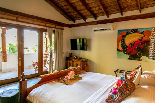 a bedroom with a large bed and a window at Almond Beach Resort at Jaguar Reef in Hopkins