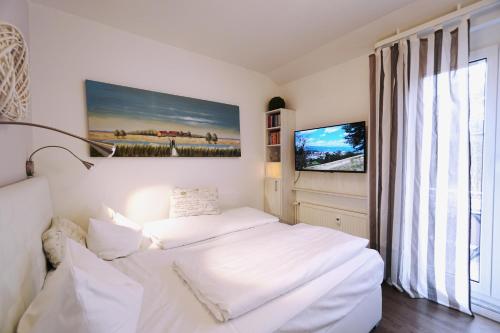 a white bedroom with a bed and a tv at Darssmuschel Dierhagen-Strand - Haus 2 in Dierhagen