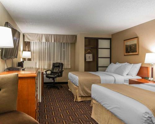 a hotel room with two beds and a desk at Wyndham Garden Medicine Hat Conference Center in Medicine Hat