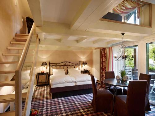 um quarto com uma cama, uma mesa e escadas em Landhaushotel Hof Wasserkuppe em Poppenhausen