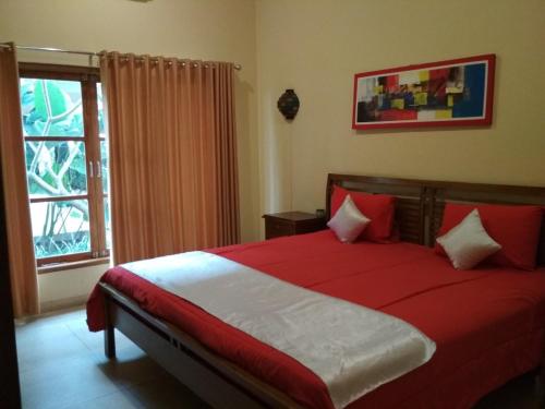 um quarto com uma cama com lençóis vermelhos e uma janela em Private pool Villa Sawah Sewon em Yogyakarta