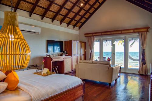 a bedroom with a bed and a couch and the ocean at Almond Beach Resort at Jaguar Reef in Hopkins