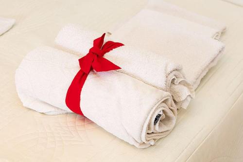 een witte handdoek met een rood lint op een bed bij Apartmani Šarić in Tučepi
