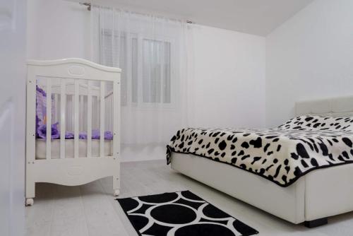 a white crib in a bedroom with a black and white bed at Apartman Mona in Podgorica