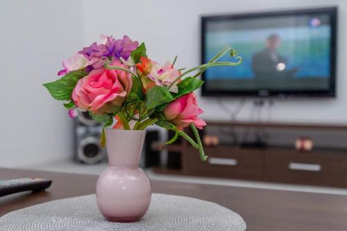 a pink vase filled with flowers on a table at Apartman Mona in Podgorica
