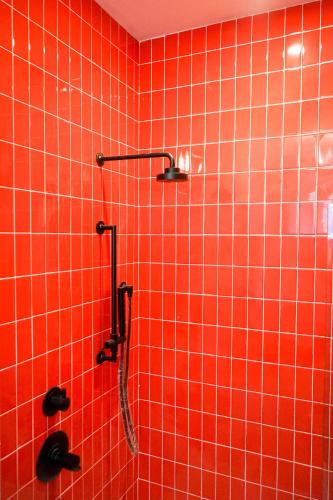 a red tiled wall with a shower in a bathroom at The Russell in Nashville