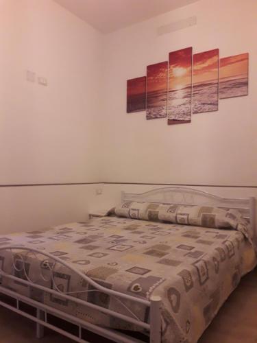 a bedroom with a bed with three paintings on the wall at Casa Caterina in La Spezia