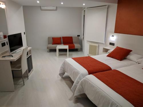 a bedroom with two beds and a desk and a television at Emperatriz I in Salamanca