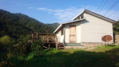 a small white house in a field with a mountain at Refugios Olmue Santa Teresa in El Maqui