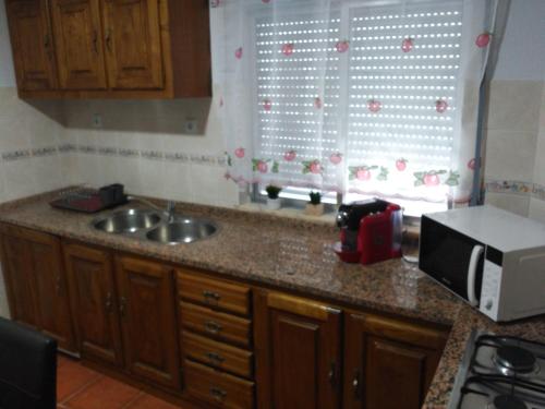 a kitchen counter with a sink and a microwave at Casa Viela in Viseu