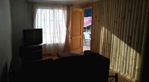 a living room with a couch and a television at Refugios Olmue Santa Teresa in El Maqui
